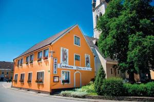 pomarańczowy budynek z wieżą zegarową w tle w obiekcie Landpension Birker - Self Check-In w mieście Weißkirchen in Steiermark