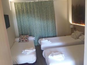 a hotel room with two beds and a window at Hostal Rural San Andrés in Torres del Río