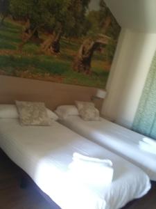two beds in a room with a painting on the wall at Hostal Rural San Andrés in Torres del Río