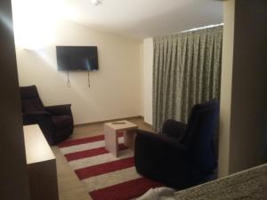 a living room with two chairs and a flat screen tv at Hostal Rural San Andrés in Torres del Río