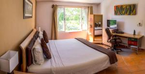 a bedroom with a bed and a desk with a computer at Casa Mi Tesoro Vacation Rooms in Playa del Carmen