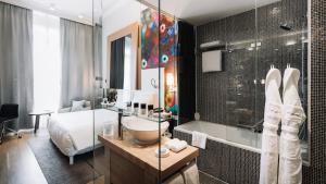 uma casa de banho com um lavatório, um chuveiro e uma cama. em Hôtel Métropole Genève em Genebra