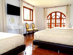 a bedroom with two beds and a table and chairs at Villa de Los Angeles in Villa de Leyva