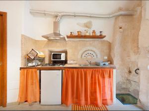 a kitchen with an orange curtain on a counter at Ostunica in Ostuni