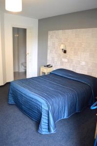 a bedroom with a bed with a blue striped blanket at Logis Auberge le petit pont in Tennie