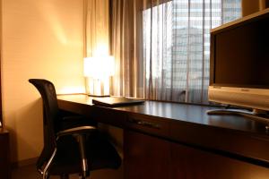a hotel room with a desk with a television and a chair at Hotel Metropolitan Edmont Tokyo in Tokyo