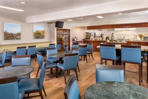 a restaurant with tables and chairs and a kitchen at Ayres Suites Diamond Bar in Diamond Bar