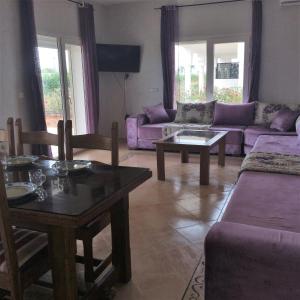 a living room with purple couches and a table at magnifique appartement Saidia in Saïdia
