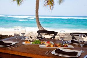 a table with plates of food and wine glasses on the beach at Villa Montaña Beach Resort in Isabela