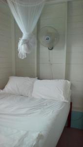 Schlafzimmer mit einem Bett mit weißer Bettwäsche und einem Ventilator in der Unterkunft Cosy Hut in Saint Georgeʼs