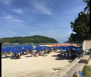 un grupo de personas sentadas en una playa con sombrillas en Pousada Pé na Areia Guarujá, en Guarujá