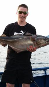 a man holding a fish in his hands on a boat at Holiday Home Kvernesfjorden in Averoy