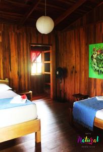 1 dormitorio con paredes de madera, 1 cama y ventana en Casa Natural Puerto Viejo, en Puerto Viejo