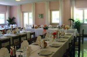 een banketzaal met tafels en stoelen met witte tafelkleden bij Hotel Ristorante Sasso Remenno in Val Masino