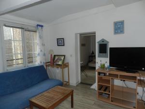 een woonkamer met een blauwe bank en een flatscreen-tv bij Appartement vue sur le port de Dieppe in Dieppe