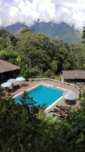 una piscina con sillas y sombrillas junto a una montaña en Hotel Esmeralda, en Coroico