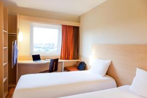 a hotel room with two beds and a desk and a window at Ibis Aguascalientes Norte in Aguascalientes