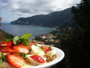 ein Teller mit Lebensmitteln mit Erdbeeren und Sahne auf dem Tisch in der Unterkunft Villa Milia in Agios Nikitas