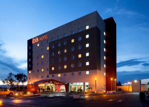 a hotel building with a store in a parking lot at Ibis Aguascalientes Norte in Aguascalientes