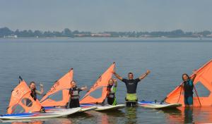 a group of people standing in the water with sailboats at Casa dos Flamingos in Murtosa
