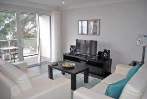 uma sala de estar com um sofá branco e uma televisão em Apartamentos 3 Praias em Ponta Delgada