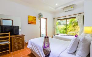 ein Schlafzimmer mit zwei Betten und einem Flachbildfernseher in der Unterkunft Sea View Luxury Villas Kata Beach in Kata Beach + 61 Fotos