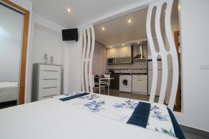 a bedroom with a white bed and a kitchen at Gaivota Holidays in Nazaré