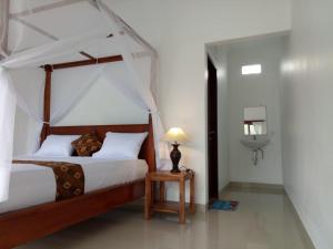 1 dormitorio con cama con dosel y lámpara en una mesa en Minory Guesthouse, en Amed