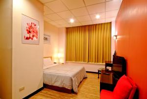 Habitación de hotel con cama y silla roja en 空中城都會商旅 en Kaohsiung