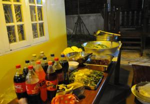 a table with bottles of soda and dishes of food at Mekong Tarawadee Villa in Tha Bo