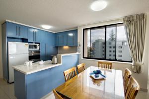 a kitchen with blue cabinets and a table with chairs at Kings Row Apartments in Caloundra