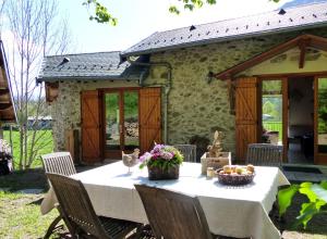 stół przed kamiennym domem z kwiatami i owocami w obiekcie Gîte de Fontainebleau w mieście Vicdessos