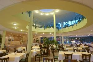 a restaurant with tables and chairs and a large ceiling at Bonita Hotel in Golden Sands