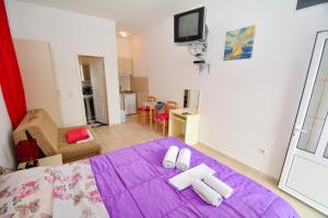 Un dormitorio con una cama morada con toallas encima. en Apartments Kristina Jaz Budva, en Budva