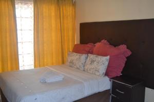 una camera da letto con un letto con cuscini e una finestra di oasis guest house a East London Altre 8 foto