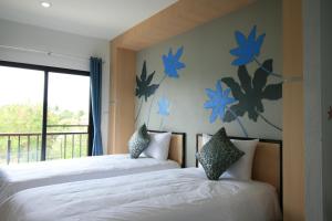due letti in una camera da letto con fiori blu sul muro di Sirimunta Hotel Chiang Rai Suite & Residence a Chiang Rai