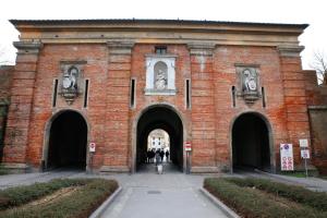 un edificio de ladrillo rojo con dos puertas con cabezas de caballo. en Luxury apartment Suite La Fontana en Lucca