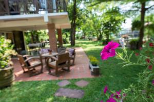 un patio con mesa, sillas y una flor rosa en Phuttal Residence, en Phra Nakhon Si Ayutthaya