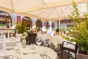 restauracja z białymi stołami, krzesłami i parasolami w obiekcie Hotel Rössle Superior w mieście Galtür
