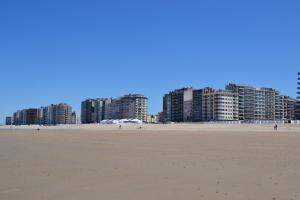 a view of the beach with buildings in the background at Het Koetshuis, op 50m van zee, voor 5 personen, centrum Westende BAD, alle comfort in Middelkerke
