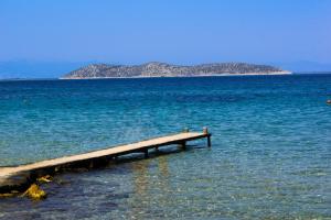a pier in the water with an island in the background at Hotel Villa Nisteri in Limenas
