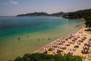 a beach with umbrellas and people in the water at Hotel Villa Nisteri in Limenas