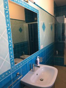a blue tiled bathroom with a sink and a mirror at Le 9 Gocce Seaview Apartment in Palau