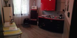 バラトンケネシェにあるNapfényのキッチン(赤いキャビネット、シンク、椅子付)