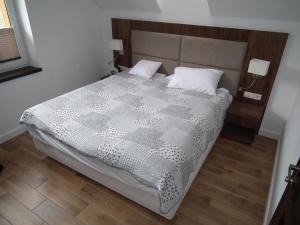 a bedroom with a bed with a gray and white comforter at Pod Modrzewiami in Krynica Zdrój