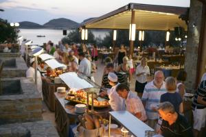 a group of people eating food at a restaurant at Lemnos Village Resort Hotel in Platy