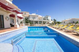 a large swimming pool with chairs and a house at Pedro Mar in Albufeira