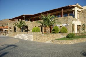 a building with palm trees in front of it at Lemnos Village Resort Hotel in Platy