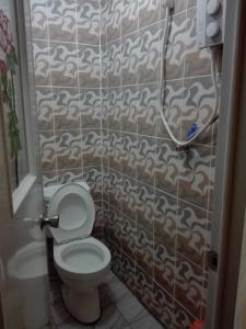 a bathroom with a toilet and a tile wall at Koreen Guest House in Banaue