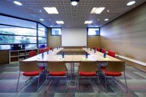 einen Konferenzraum mit einem Tisch, Stühlen und einem Whiteboard in der Unterkunft Exe Madrid Norte in Madrid